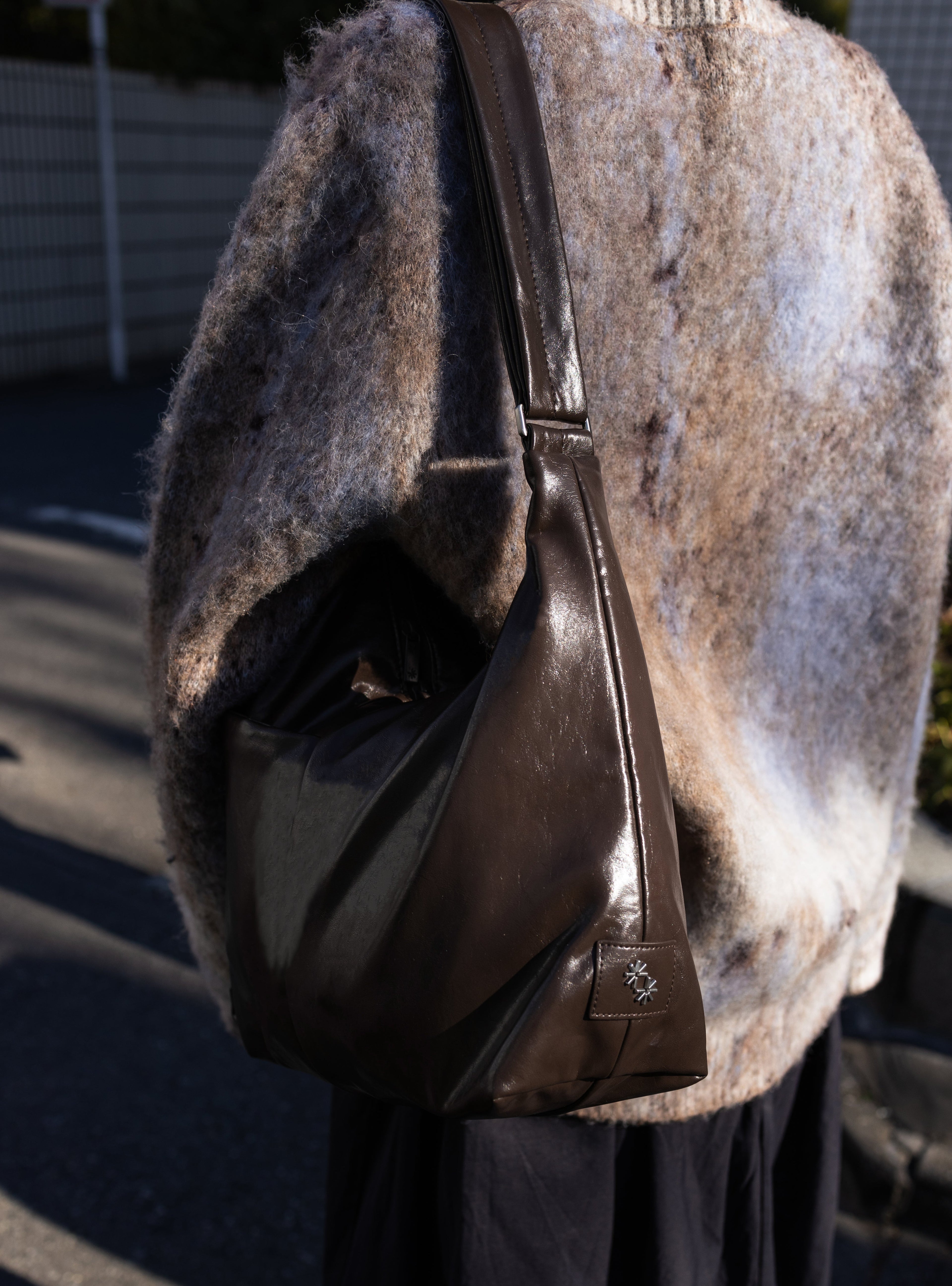 Woman carrying the Midi Arc slouchy hobo bag in dark brown vegan leather as shoulder bag